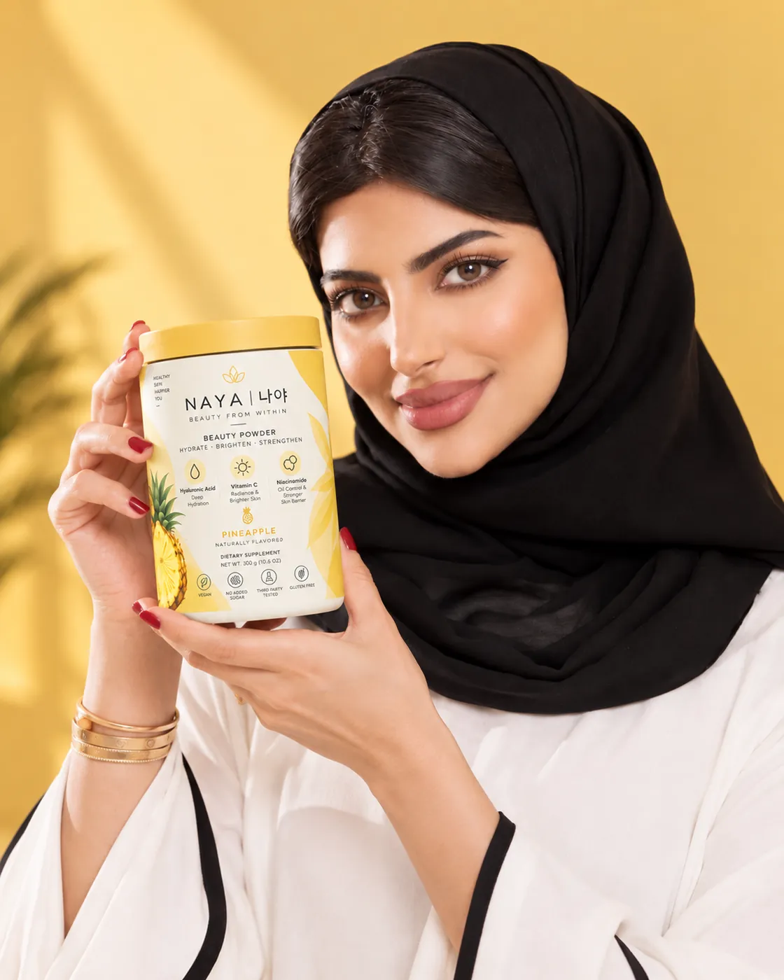 امرأة تحمل عبوة NAYA Beauty Powder بنكهة الأناناس